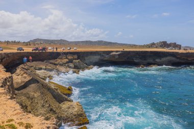 Kıyı şeridindeki turistleri görmek, doğal mağarada yüzmek. Aruba. Atlantik Okyanusu. 