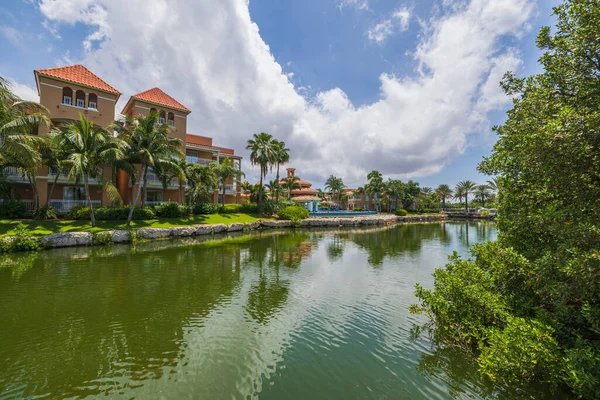 Gorgeous landscape view of hotel grounds with green trees courses and lake against blue sky with white clouds background. Aruba.