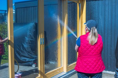 Kadın yıkamadan önce camları suyla kaplıyor. İsveç. 