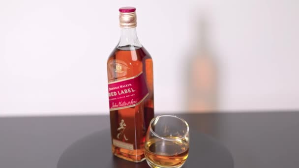 Närbild Roterande Flaska Johnnie Walker Red Label Whisky Och Glas — Stockvideo