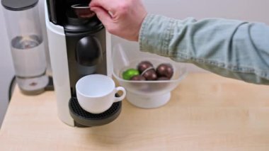 Kapsül kahve makinesine kahve kapsülü koyarken insanın elinin yakın görüntüsü..