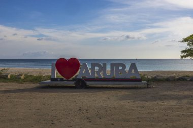 Gün batımında Aruba 'yı çok sevdiğim büyük beyaz harflerin yakın görüntüsü. Büyük kırmızı kalp sözcük sevgisinin yerini aldı. Aruba. Oranjestad.