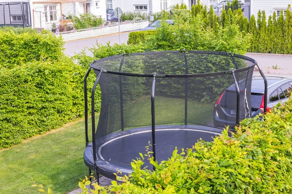 stock image Beautiful view of trampoline with protective net in garden of villa in suburban village. Sweden.