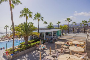 Palmiye ağaçları ve mavi gökyüzü arka planındaki açık havuz manzarası. RIU Vistamar Oteli, Gran Canaria, İspanya.