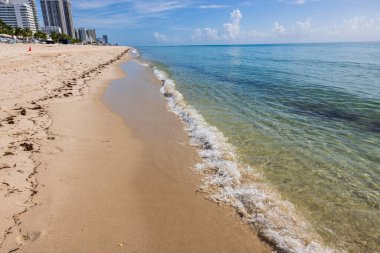 Ufukta mavi gökyüzü ve binalarla birleşen güzel kıyı şeridi manzarası. Miami Beach, Florida, ABD. 