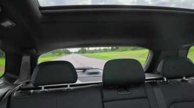 Deri koltuklar ve otoyolda giden yeni siyah elektrikli arabanın panoramik sunroof 'u ile güzel bir iç görünüş. İsveç.