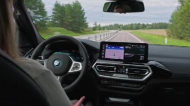 BMW iX3 M spor kullanan güzel bir kadın manzarası. Kontrol gösterge paneli ve panoramik sunroof 'un iç görünümü. 