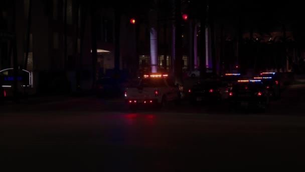 点滅するライトが付いている多くの警察車が付いているコリンズ アベニューの夜景 マイアミビーチ — ストック動画
