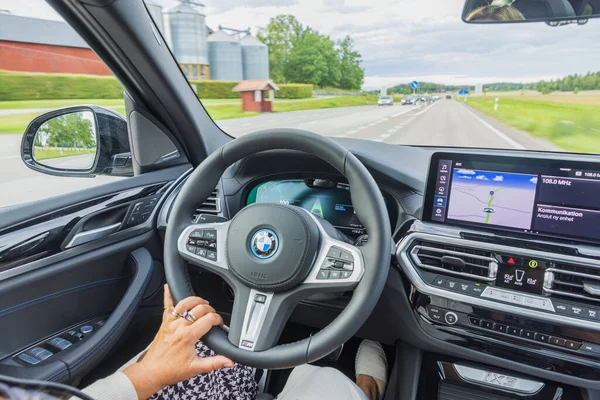 Otoyoldaki elektrikli araba BMW iX3 M-sport 'un güzel iç manzarası. Araçta kadın sürücü. 