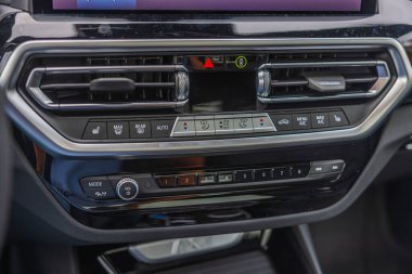 Multimedya ve klima kontrol düğmeleri olan BMW iX3 M-spor elektrikli arabanın kontrol panelinin yakın görüntüsü.