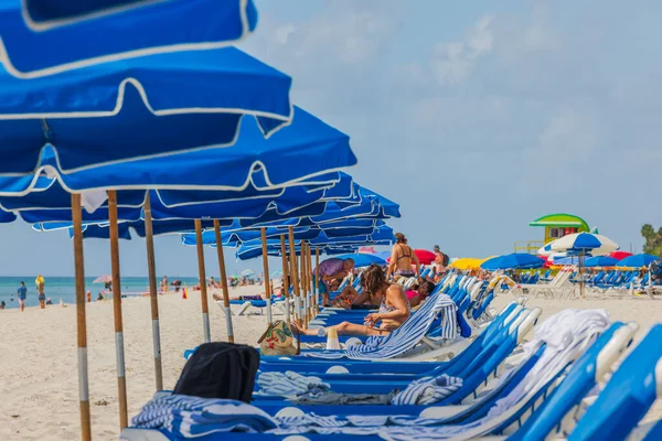 Kumsaldaki güneş yatakları sırasındaki insanların yakın görüntüsü. Miami Beach, Florida, ABD