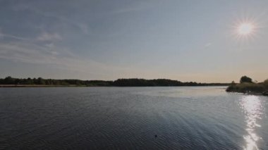 Ormanın arka planında gün batımında güzel bir göl manzarası. İsveç.