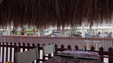Palmiye yapraklarıyla kaplı çatıdaki açık hava otel restoranının iç manzarası.. 