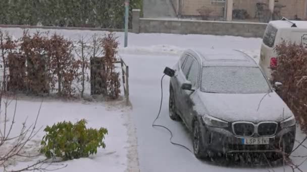 Bmw Ix3 冬の降雪中にプライベートハウスの駐車場で充電する電気自動車のビュー — ストック動画