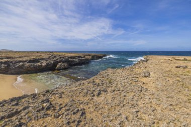 Aruba adasındaki Karayip Denizi 'ndeki kayaların arasındaki kumlu sahilin güzel manzarası..