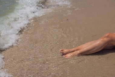Kumsalda gelen dalgalarda güzel bir kadın bacağı manzarası. Miami Plajı.