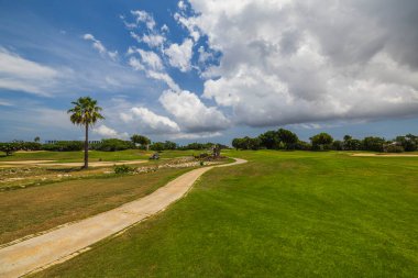 Arka planda yeşil çimen golf sahası Aruba adasında beyaz bulutlu mavi gökyüzü. 