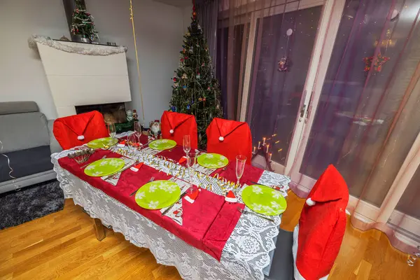Beautiful view of interior of room with served Christmas table and Christmas tree decorated with New Years toys.  Sweden.