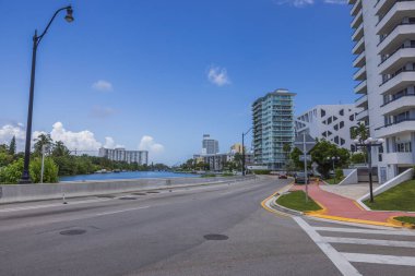 Güneşli yaz gününde Miami Plajı 'nın güzel şehir manzarası. Yol, diğer tarafında yüksek modern binalar bulunan liman boyunca uzanıyor. ABD.