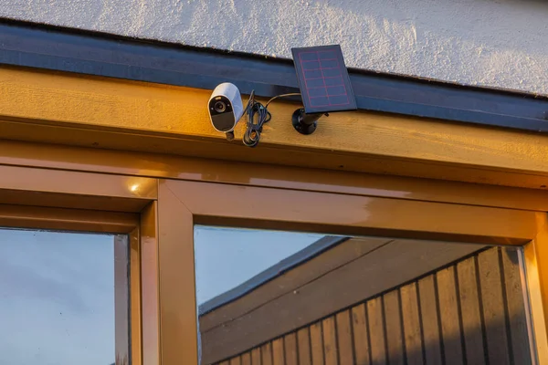 View of high-tech outdoor security camera equipped with solar panel mounted on house facade. Sweden.