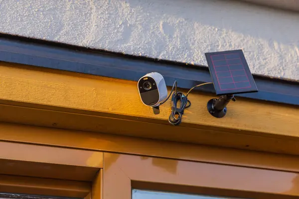 Close up view of high-tech outdoor security camera equipped with solar panel mounted on villa\'s facade. Sweden.
