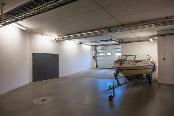 駐車場の地下ガレージの輸送クレードル上の白いモーターボート スウェーデン ストック画像