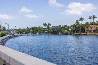 Miami Plajı 'ndaki lüks villaların yanında güzel bir rıhtım manzarası var. Yat park alanı ve mavi gökyüzü arkaplanındaki palmiye ağaçları beyaz bulutlu..