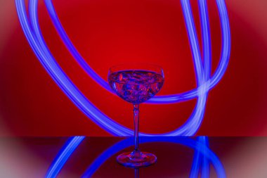 Kırmızı arka planda kristal bardakta buz küpleri olan güzel bir içki manzarası.. 