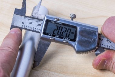 İnsan alüminyum borunun boyutunu ölçmek için elektronik kalibreli kullanıyor..