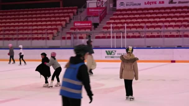 子供たちは屋内アイスリンクでスケートをしている 1人の少年がスパイラルエクササイズをしている — ストック動画