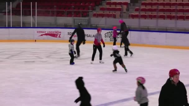 观看儿童和成年人在体育场的冰球场上滑冰的情景 — 图库视频影像