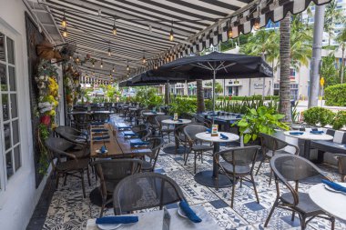 Şehir restoranının dışını şık masalarla aydınlık ve güneşli bir günde ziyaretçileri ağırlamaya hazır bir şekilde davet etmenin görüntüsü. Miami Plajı. ABD. 
