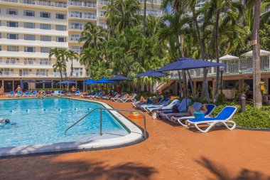 İnsanların şemsiyeler altında dinlendiği açık yüzme havuzunun olduğu otel manzarası çok güzel. Miami Plajı. ABD.