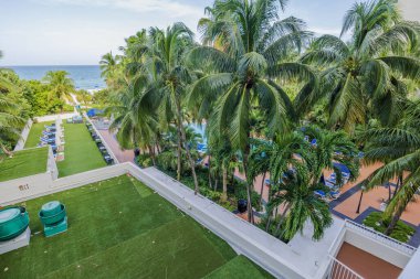 Atlantik Okyanusu 'nun arka planında palmiye ağaçları ve güneş panelleri olan güzel bir otel manzarası. Miami Plajı. ABD.