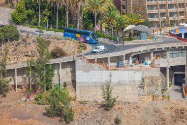 Karmaşık dağlık alandaki inşaat alanının üzerindeki yol yüzeyinden geçen renkli turist otobüsünün görüntüsü. Büyük Kanarya, İspanya. 