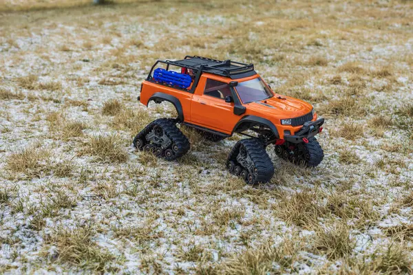 Close up view of orange radio controlled toy off-road vehicle with caterpillar wheels. Sweden.