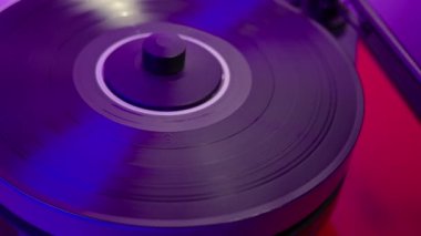 Adamın elleri, arka planda mavimsi ışık eşliğinde müzik dinlemeye başlamak için yüksek kaliteli plak çalar tonunu vinil diskin üzerine indiriyor..