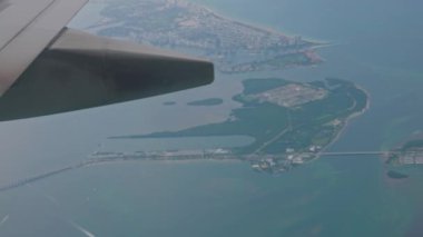Uçağın iniş için inişi sırasında pencereden, Atlantik Okyanusu 'nun mavi sularını ve Miami' nin şehir manzarasını gözler önüne serer.. 
