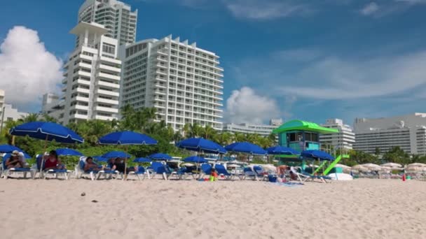 サンラウンジャー サン傘 ライフガードステーション 海岸ビルを背景にした白い砂浜の景色 マイアミビーチ アメリカ合衆国 — ストック動画