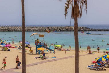 Gran Canaria 'daki Atlantik Okyanusu' nun kumlu kıyısında donanımlı plajlarda dinlenen turistlerin yanı sıra şemsiyeler ve şezlonglar da bulunuyor. İspanya. 