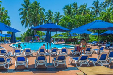 Misafirlerin şemsiyelerin altında güneşlendiği açık havuz manzaralı otel manzarası. Miami Plajı. ABD. 