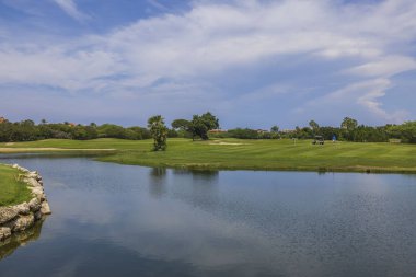 Genç çiftin Aruba adasında golf oynadığı göl manzaralı golf sahası manzarası.