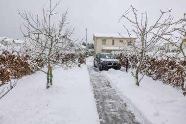Soğuk bir günde otoparkta karla kaplı yürüyüş yolu ve araba kış manzarası temizlendi. İsveç.