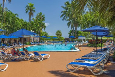Turistler güneşli bir günde otel havuzunda dinleniyorlar. Miami Beach, ABD.