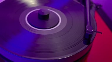 Yüksek kaliteli bir plak çaları aktifleştiriyor, arka planda hafif mavimsi bir parıltıyla müziği başlatmak için tonearm 'ü vinil diskin üzerine yavaşça indiriyor. İsveç.