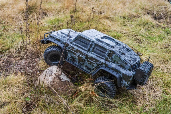 Close up view of radio-controlled toy off-road vehicle in camouflage colors, navigating rough terrain. Sweden.