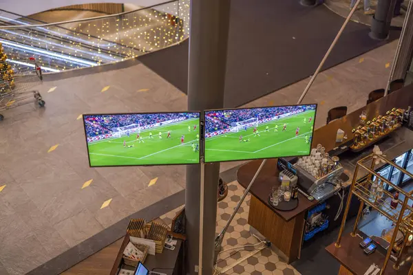 Liverpool ve Arsenal arasında Premier League maçı yayınlayan iki büyük monitörlü spor barının yukarıdan aşağı görüntüsü. 