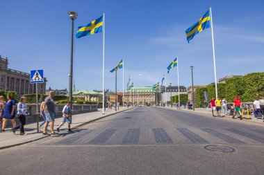 Stockholm 'ün güzel manzarası, Stockholm' ün merkezindeki bir yoldan geçen yayalar ve güneşli bir yaz gününde İsveç bayrakları.. 