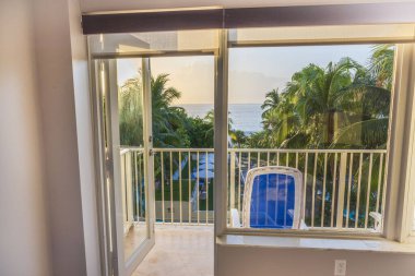 Odadan, otelin açık balkon kapısından güzel bir manzara. Atlantik Okyanusu 'nun arka planına bakan hindistan cevizi palmiyeleri. Miami Plajı.