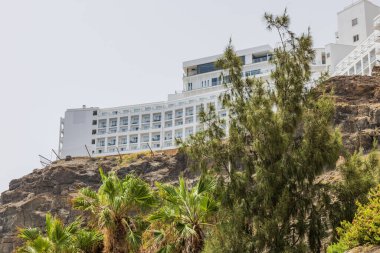 Gran Canaria dağının tepesindeki beyaz bir otelin çarpıcı manzarası bulutsuz, soluk mavi bir gökyüzünün arkaplanı. İspanya.